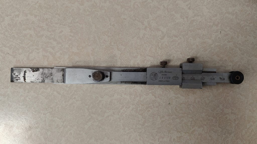 Vintage Alfa Romeo valve clearance adjustment tool lying on a workshop bench